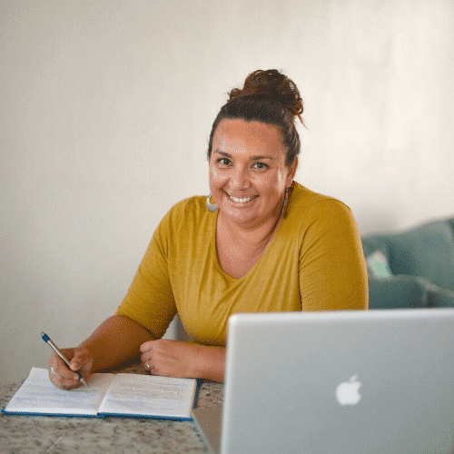 A person is sitting at a laptop with a smile on their face, using a personal computer indoors.