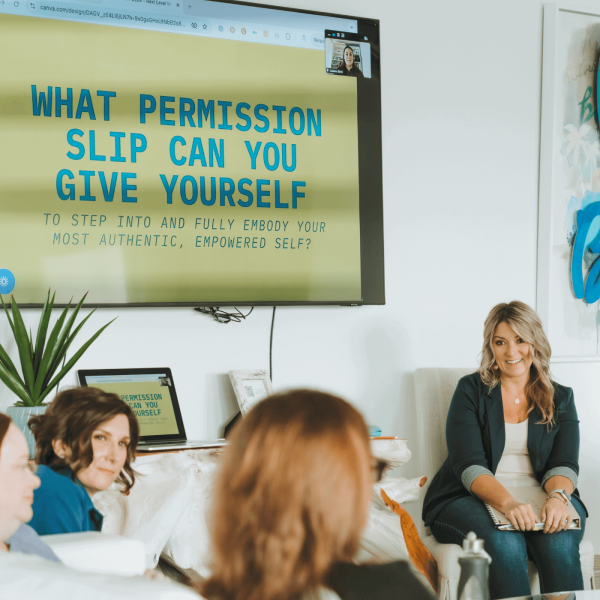 A group discussion in a modern room features a motivational presentation on a large screen, encouraging self-empowerment and authentic living.